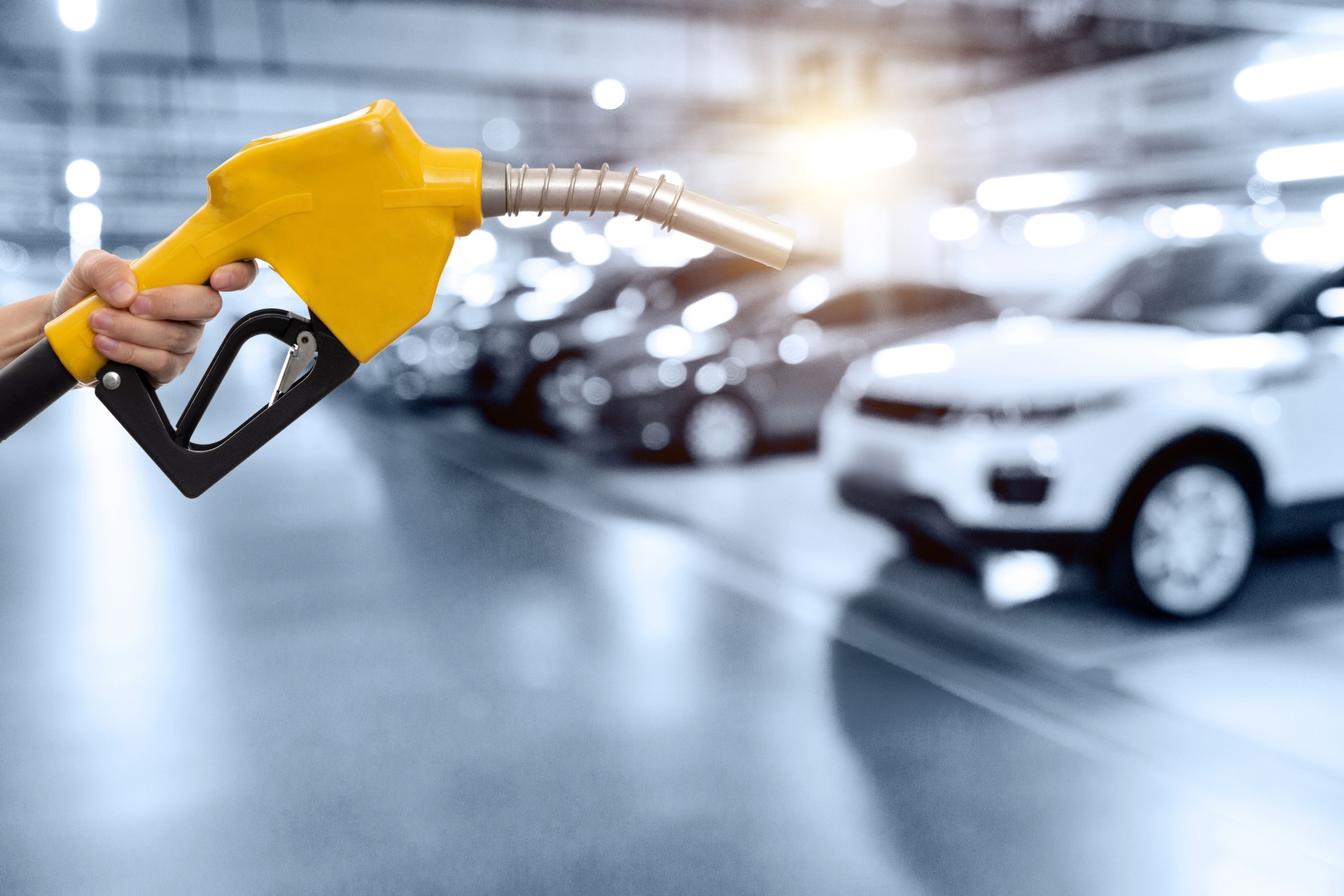 Human hand holding gasoline nozzle in the parking lot